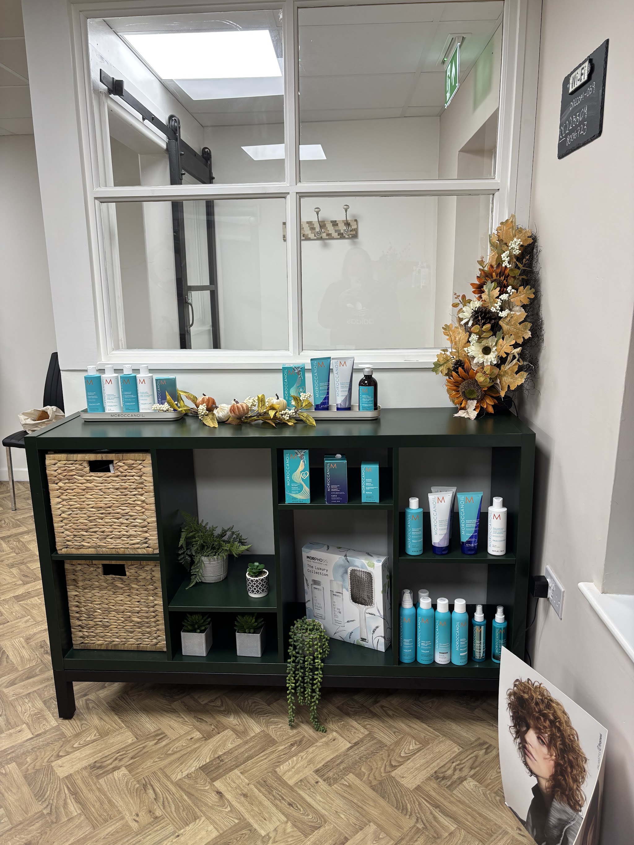 Dark green shelving with hair products, baskets and autumn flowers